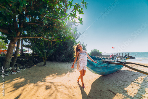 Happy Romantic honeymoon couple on the beach sitting on the sand near old fishing boat and looking each other kissing. Husband with his wife near the ocean. Sri lanka. Hikkaduwa.