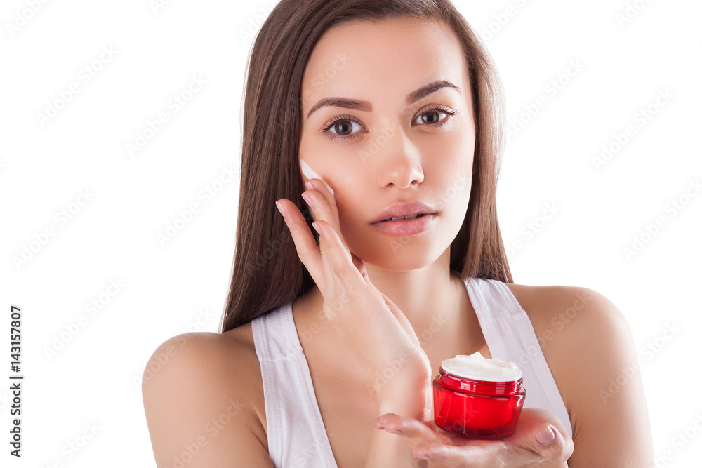 Pretty woman with perfect skin holding a tube with face cream. Young girl with hands on the front. Red jar of cream. Close-up. Isolated background. Beautiful woman wearing a face and hands cream. Pretty woman with perfect skin holding a tube with face cream. Young girl with hands on the front. Red jar of cream. Close-up. Isolated background. Beautiful woman wearing a face and hands cream.