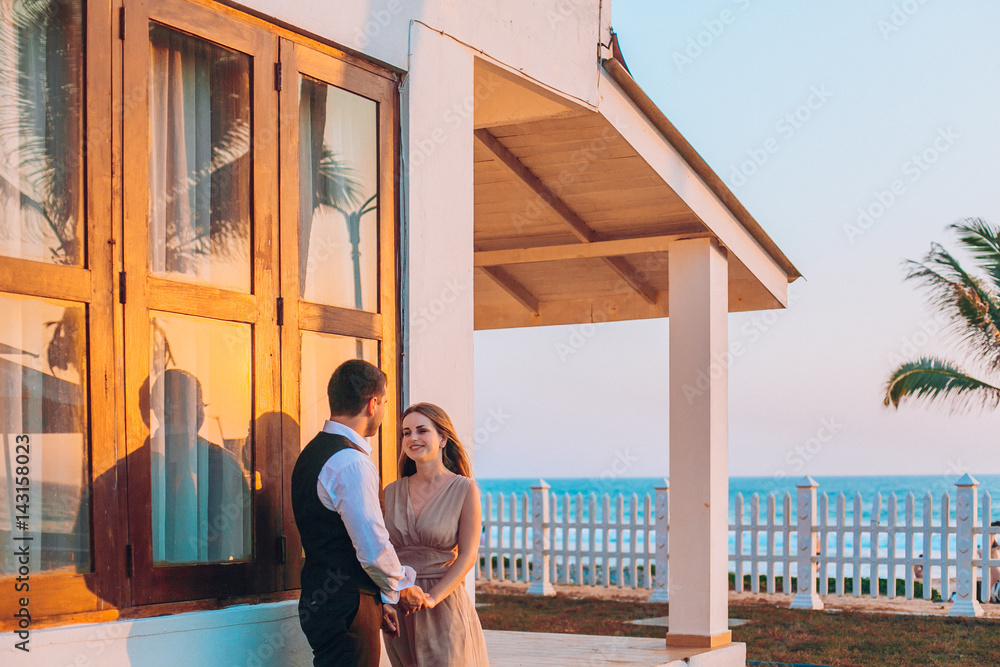 lovely couple stay near  beach hut around ocean or sea palms and sand.