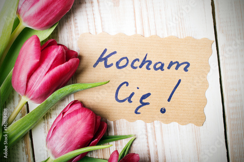 Polish word LOVE and bouquet of tulips on wooden background