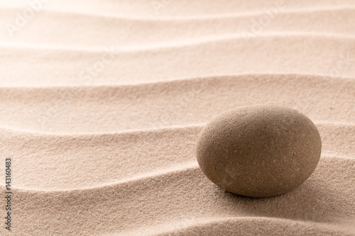 Round stone on beach sand. Zen meditation cocept for relaxating and concentration or spa wellness theme for purity and balance. Background with copy space. photo