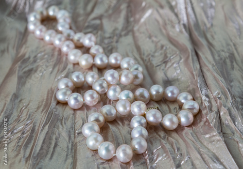 Pink pearl necklace on dusty rose pink pleated satin background close up - photo