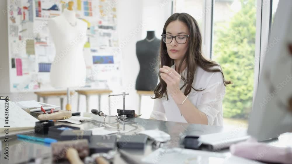Jewelry designer working in studio with tools, materials & jewelry items. Jewelry designer working in studio with tools, materials & jewelry items.