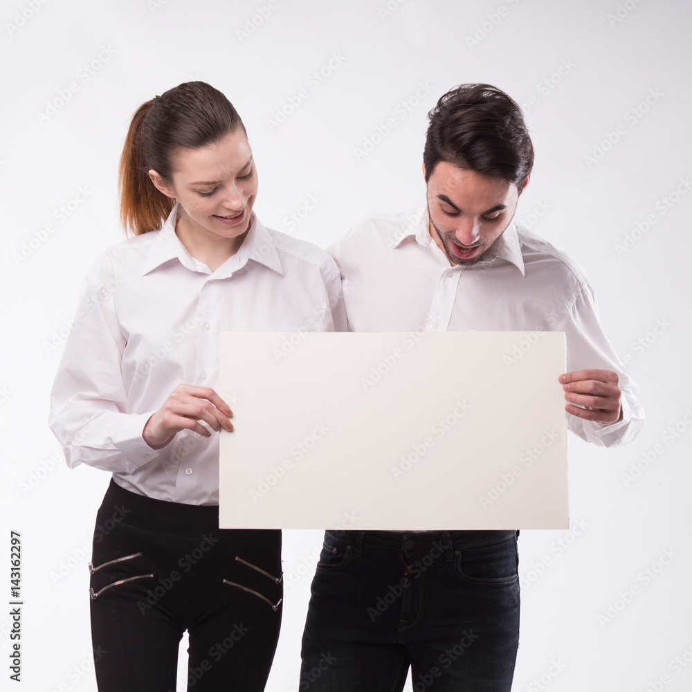 Young happy couple showing presentation pointing on placard over gray background Young happy couple showing presentation pointing on placard over gray background