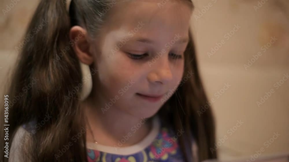 Little pretty girl with a tablet computer on a sofa at home Little pretty girl with a tablet computer on a sofa at home