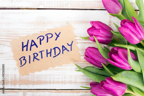 Birthday card and tulip bouquet on white wooden background