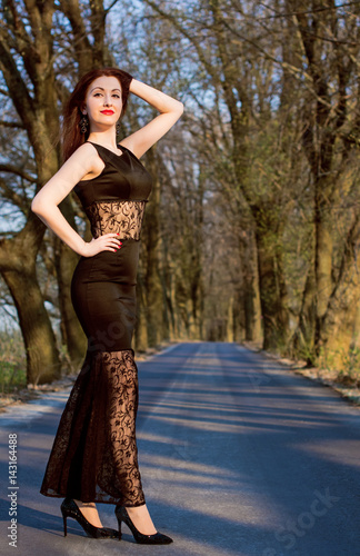 Beautiful young redhead woman in black theatre lace dress, glitter shoes and vintage jewelry, ratro make up, on a nature near forest, road, on backstage, vintage backaround, have inspire mood, star photo