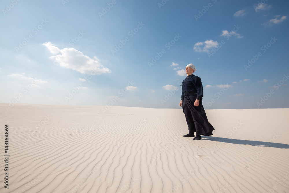 Man in traditional clothes stands and meditates in the middle of desert