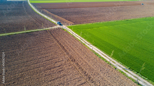 Una jeep attraversa una strada di campagna, vista aerea di un’auto fuoristrada che percorre una strada sterrata che attraversa dei campi coltivati. Viaggiare, fare vacanze nella natura 