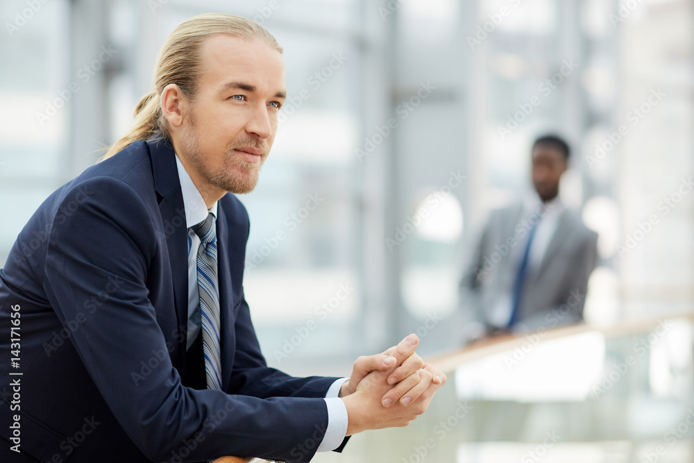 Young confident employer or business leader on background of colleague Young confident employer or business leader on background of colleague