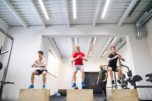 Men in gym with trainer exercising on fit boxes. photo