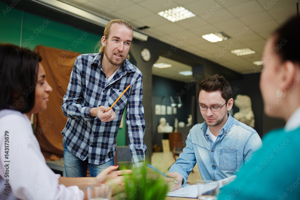Confident man explaining results of work over new project to colleagues Confident man explaining results of work over new project to colleagues