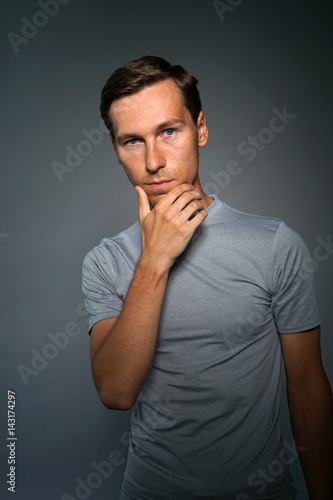 Thoughtful young man on gray background.