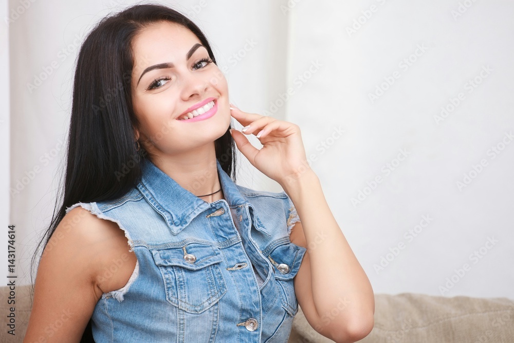 Relaxed casual brunette in blue cardigan and In blue jeans sits on the couch Relaxed casual brunette in blue cardigan and In blue jeans sits on the couch