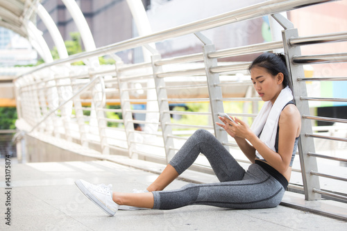 Asian woman sitting and use smartphone when finish for exercise, outdoor exercise concept. Free Download Asian woman sitting and use smartphone when finish for exercise, outdoor exercise concept. - GFXLoad