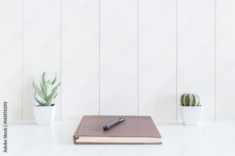 Notebooks diary and pen with cactus flowers vase on white desk and wooden background with copy space Notebooks diary and pen with cactus flowers vase on white desk and wooden background with copy space