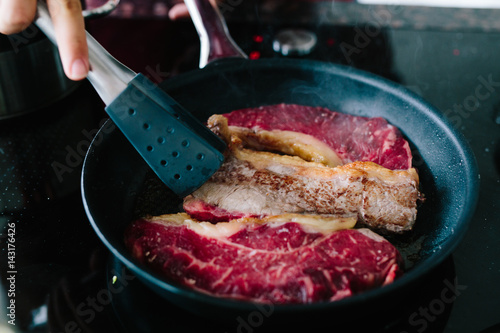 Anbraten von drei Steaks in der Pfanne beim Wenden