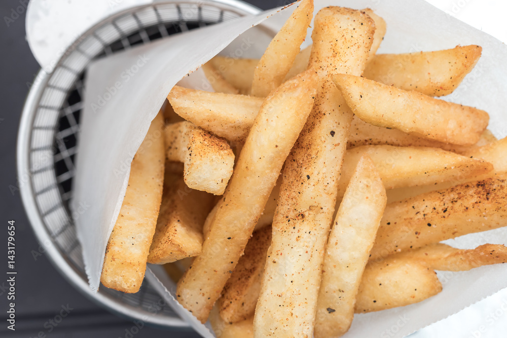 Potatoes fries in a little white paper bag on wood board Potatoes fries in a little white paper bag on wood board