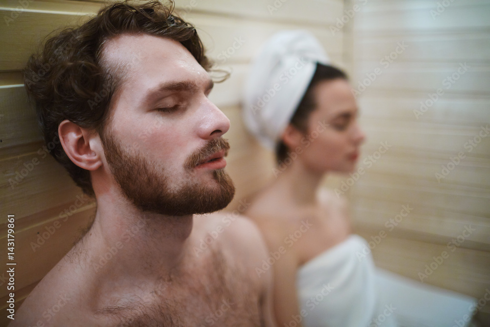 Fototapeta premium Peaceful man and his wife relaxing in sauna at leisure