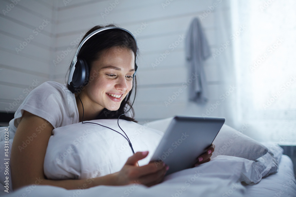 Girl with modern gadget watching something interesting online Girl with modern gadget watching something interesting online