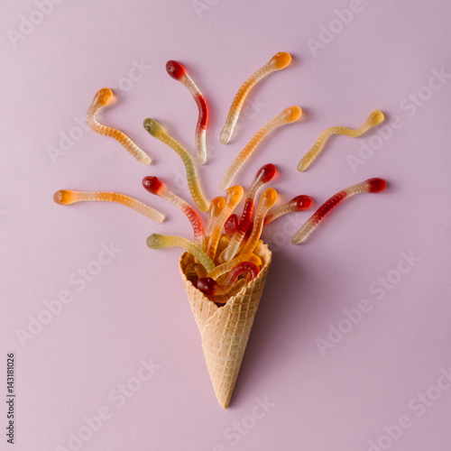 Ice cream cone with gummy candy on pastel pink background. Minimal food concept. Flat lay.