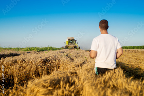 Farmer at wheat field checking online internet progress.