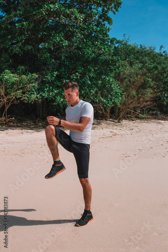 Close up of young muscle man body, during sunshine, on the beach of Bali Fitness man exercising before running