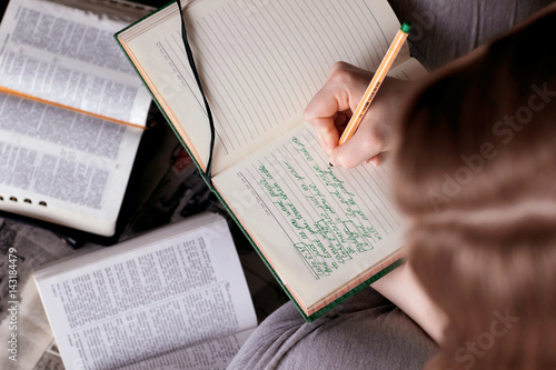 Girl holding a Bible. Сoncept for faith, spirituality and religion. Hand with pen taking notes from an open book Bible.