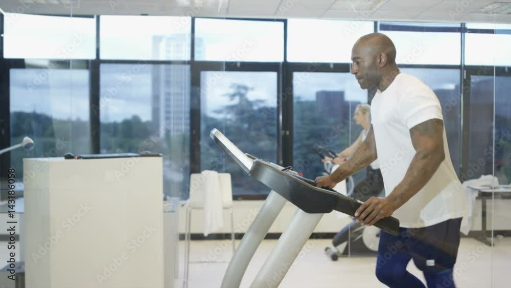 Man using treadmill in modern gym with view of natural environment on video screen. Man using treadmill in modern gym with view of natural environment on video screen.