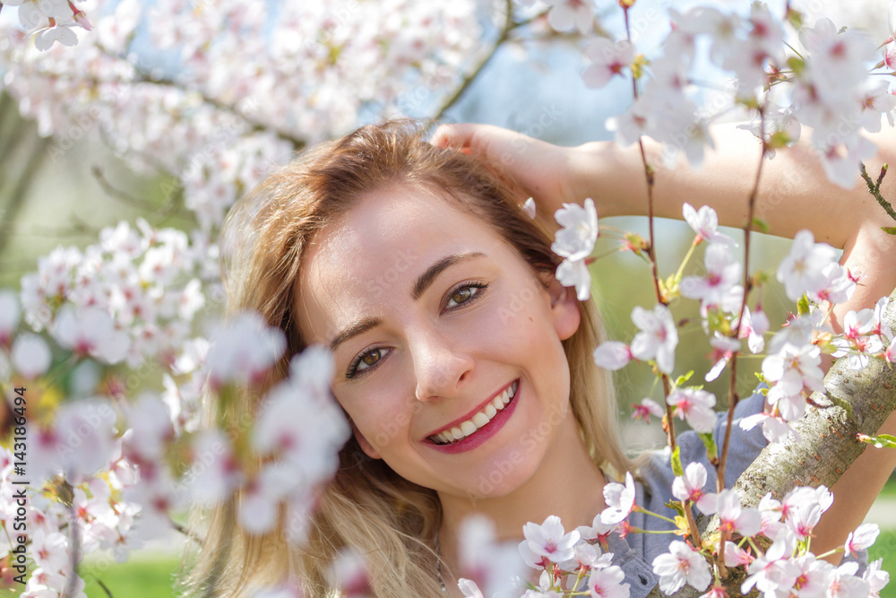 Obraz premium Beautiful happy young woman in a flowering spring garden