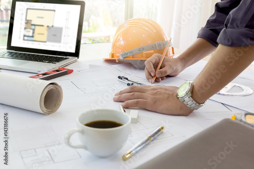 Interior designer discussing data and digital tablet and computer laptop with business document and graphics design diagram on wooden desk as concept