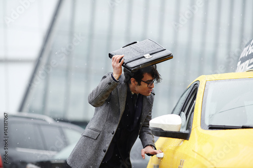 Bild auf Leinwand Portrait of disheveled Middle-Eastern businessman hurrying to catch taxi cab on