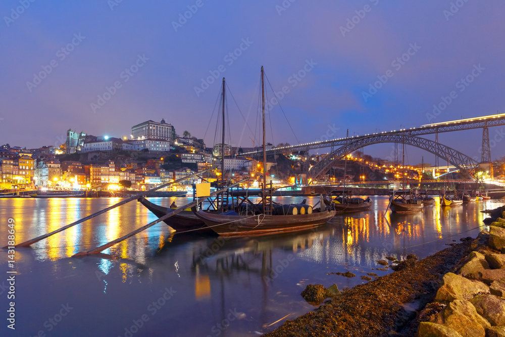 Traditional rabelo boats with barrels of Port wine on the Douro river, Ribeira and Dom Luis I or Luiz I iron bridge on the background, Porto, Portugal.