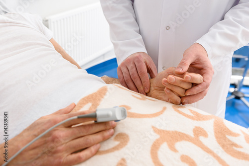 Physician keeping hand of ill male