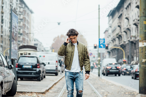 Handsome young man walking outdoor in the city talking smart phone - technology, social network, city life concept