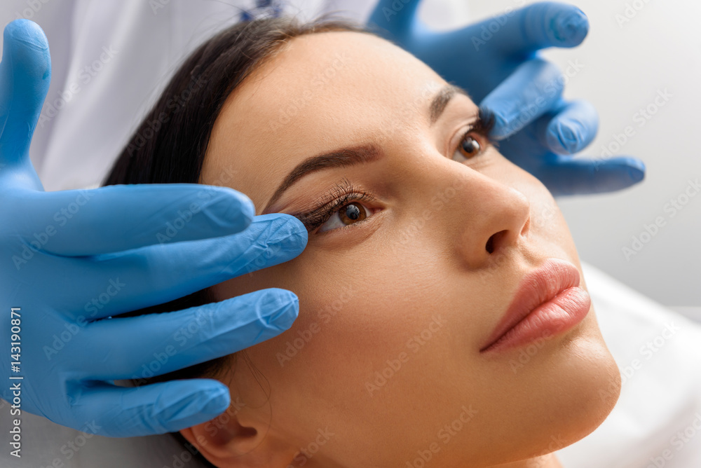 Unconcerned female taking face massage in cosmetology Unconcerned female taking face massage in cosmetology