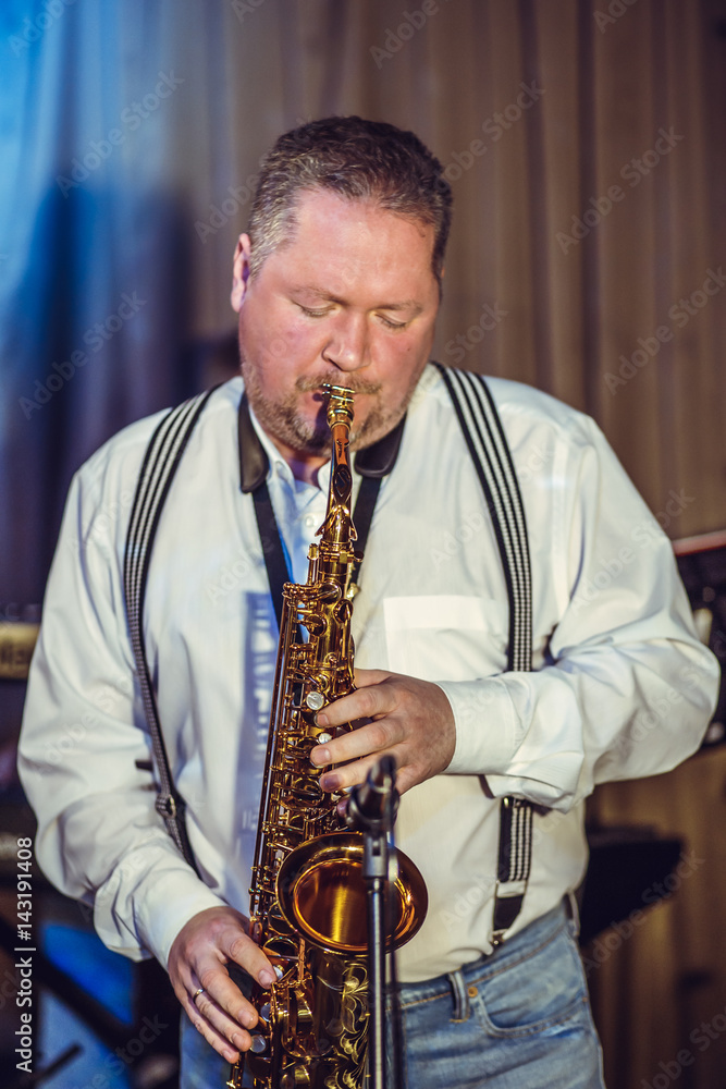 Fototapeta premium Concert in the restaurant. A middle-aged man, of European appearance, plays the saxophone.