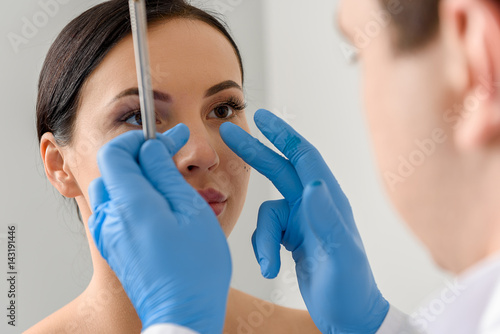 Physician examining face of serene female photo