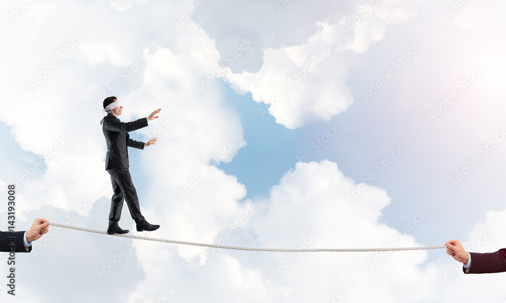 Business concept of risk support and assistance with man balancing on rope Business concept of risk support and assistance with man balancing on rope