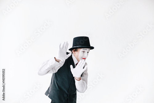 Scarred mime holds his hands up trying to hide from something