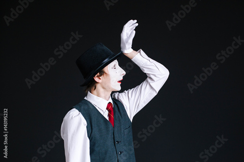 Mime raises his hand up posing on black background