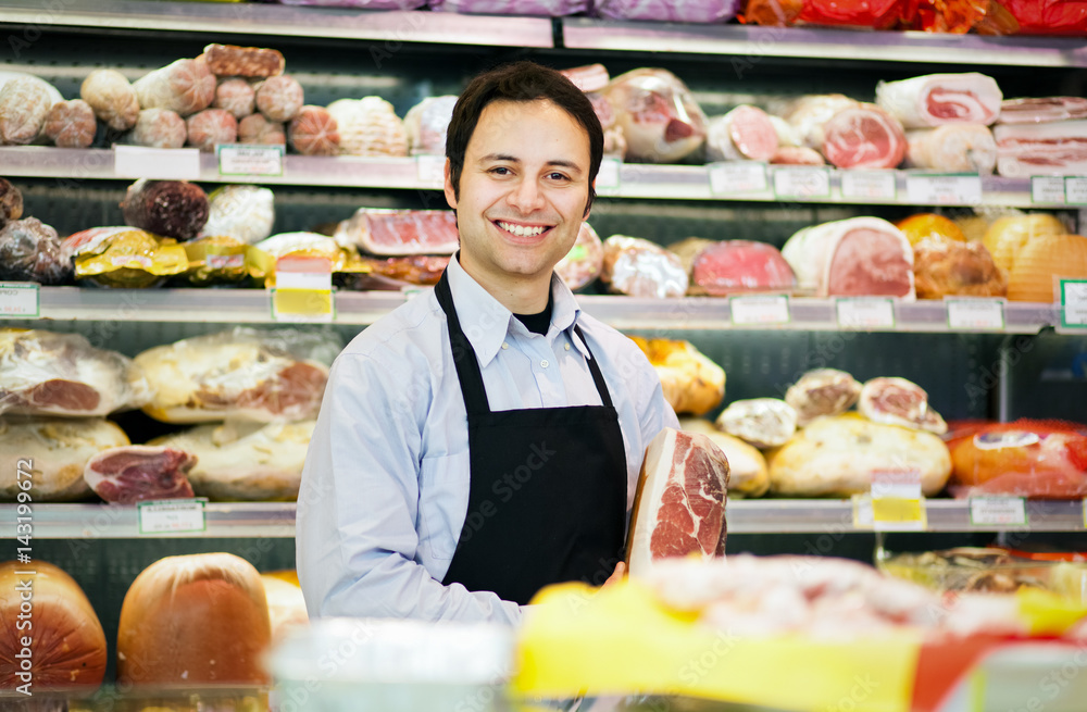 Smiling butcher in his grocery store