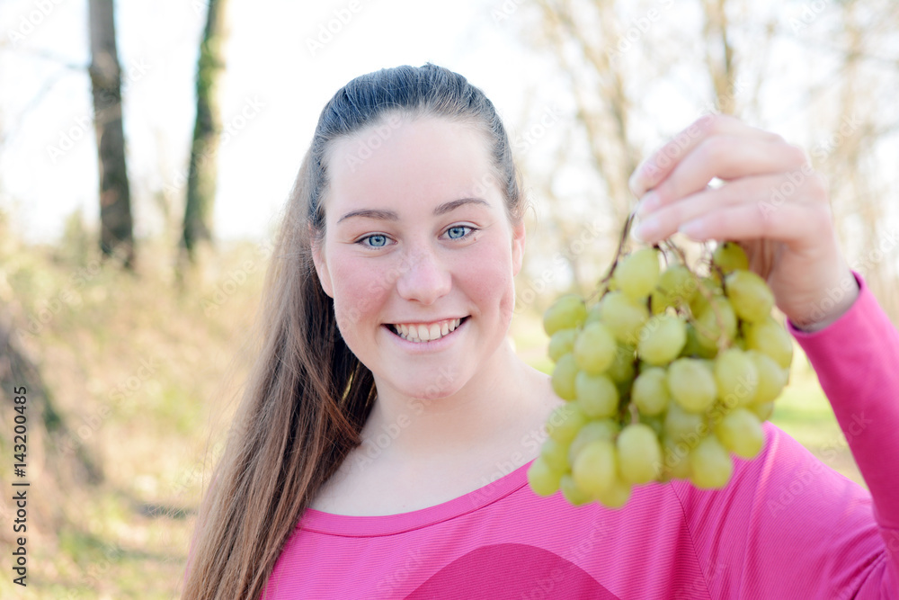 Beautiful young woman eating grapes in the park.