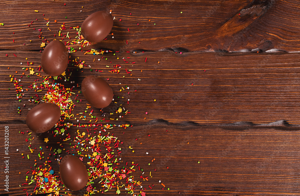 Naklejka premium Delicious chocolate Easter bunny and eggs on wooden background