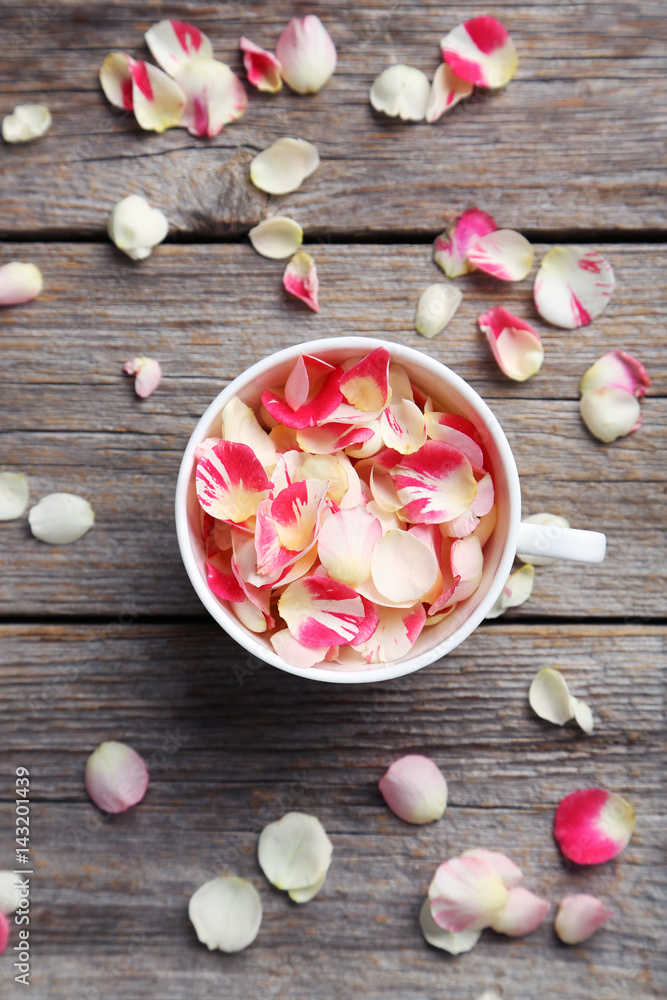 Rose petals in white cup on grey wooden table Rose petals in white cup on grey wooden table