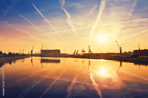 Sunrise over crane silhouettes in Szczecin harbor, Poland.