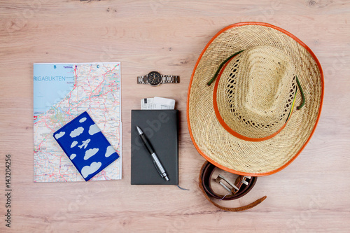  Top view of essentials for modern young person. Objects of a traveller isolated on wooden background: hat, leather belt, watch, passport, map and notebook with pen photo