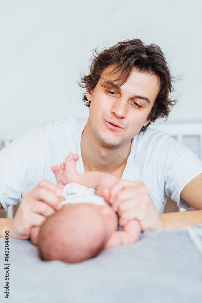 Emotional vertical portrait of father speaking and caressing newborn baby son on the bed. Emotional vertical portrait of father speaking and caressing newborn baby son on the bed.