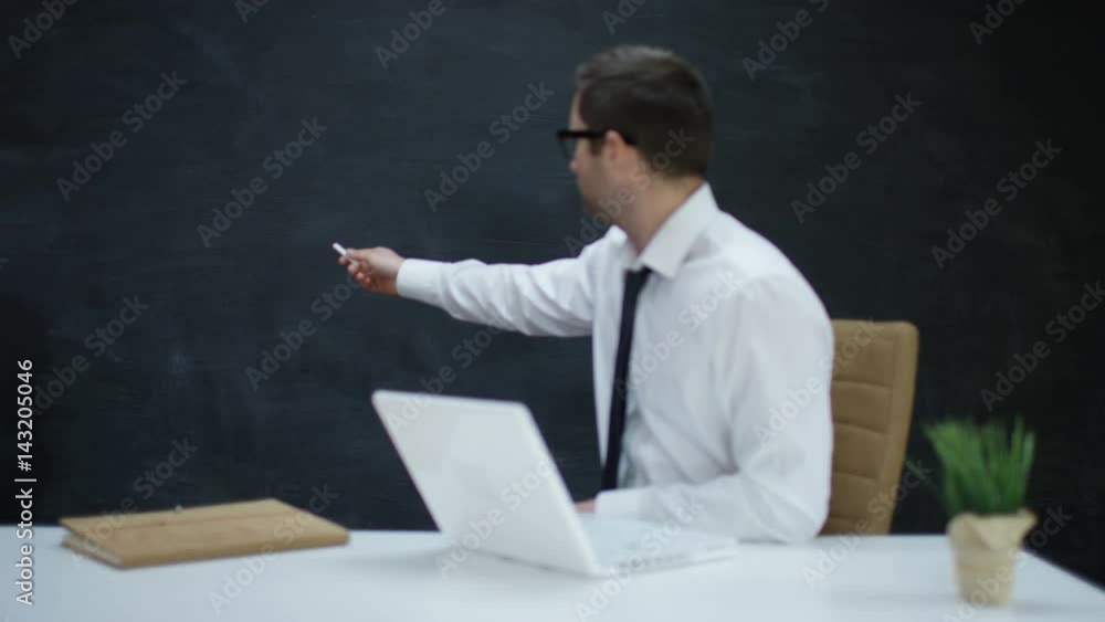 Businessman with laptop moving his hand as if underlining a word on chalkboard Businessman with laptop moving his hand as if underlining a word on chalkboard