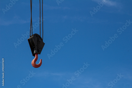 A real red crane hook on the blue sky background